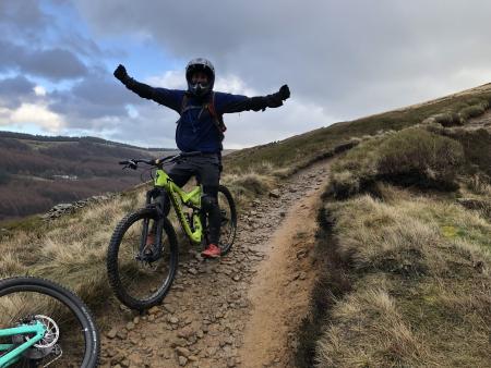 man wearing full face helmet and straddling his bike with arms in the air.