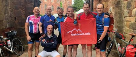 group of cyclists holding OutdoorLads flag