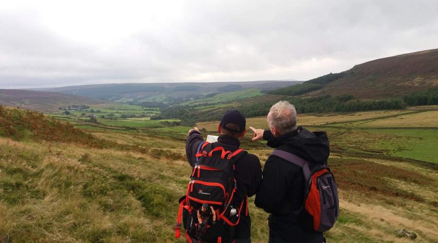 Two members navigating looking into thr hills