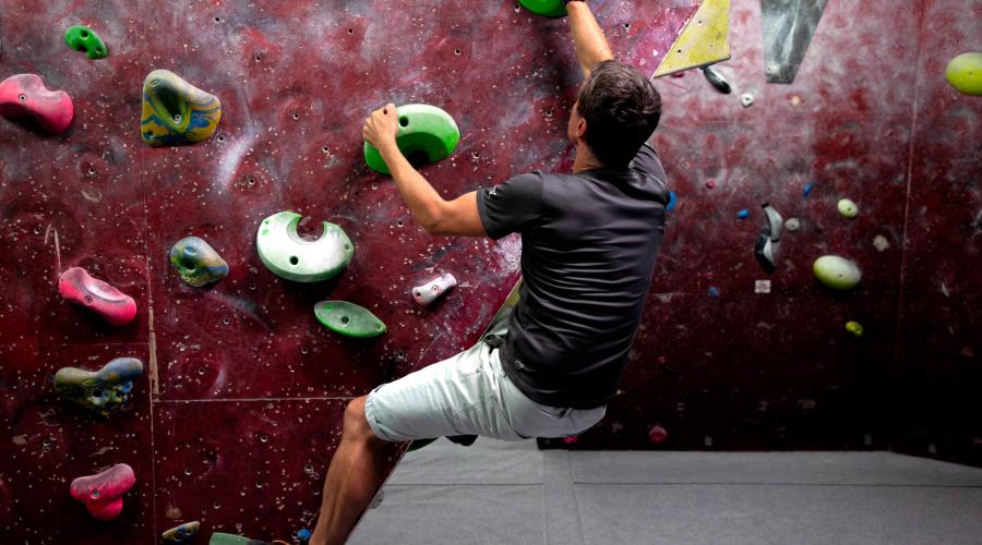 Boulderer climbing up a wall