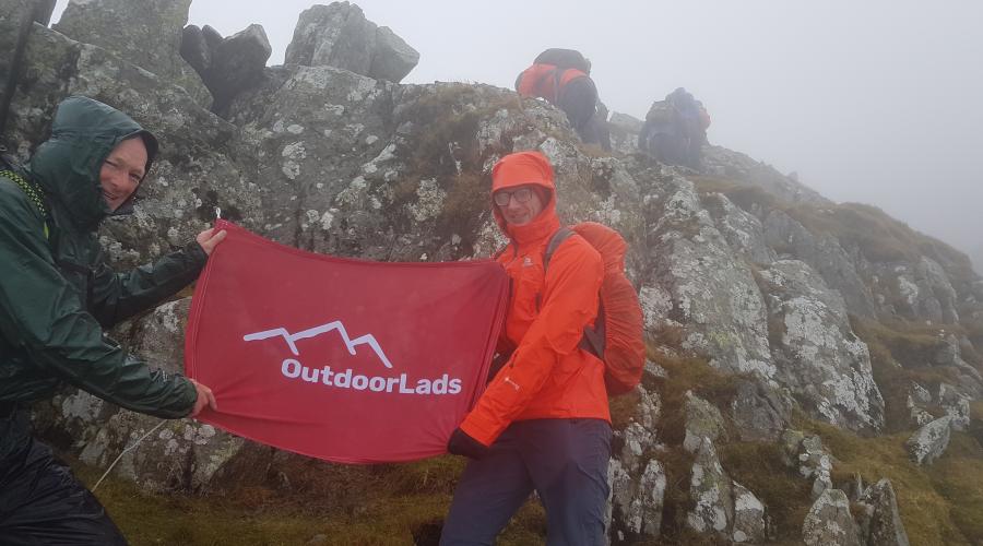 2 Guys holding a flag in front of rocks