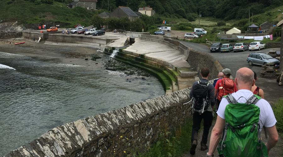 Hikers following the coastal path into a small harbour