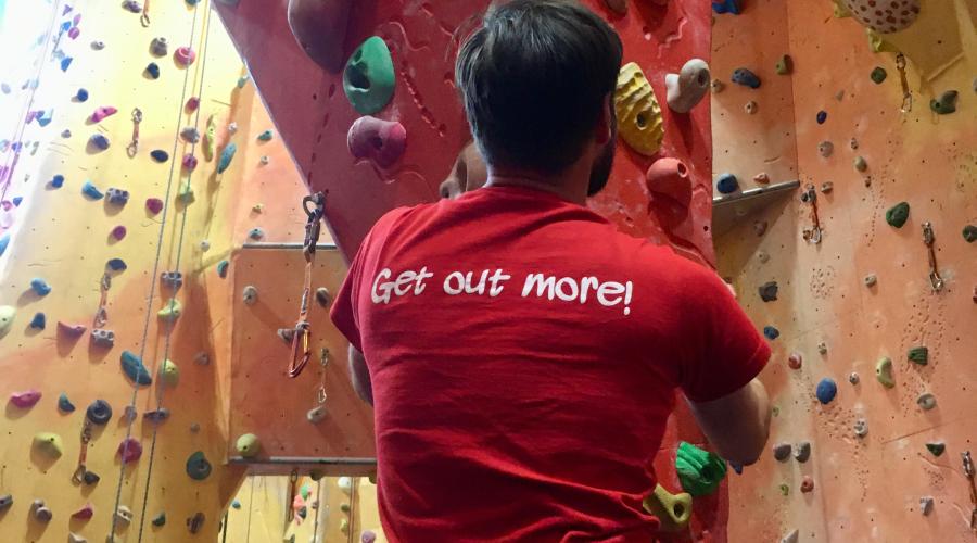 Climber climbing an indoor stalactite with the ODL Get Out More logo