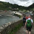 Hikers following the coastal path into a small harbour