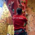 Climber climbing an indoor stalactite with the ODL Get Out More logo