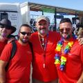 4 men in red t shirts smiling with pride float behind