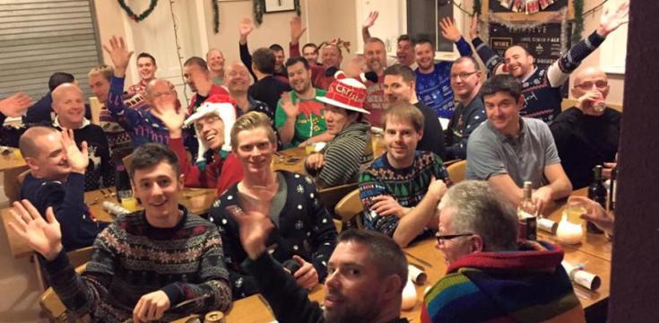 Guys at a youth hostel Christmas party wearing Christmas hats 