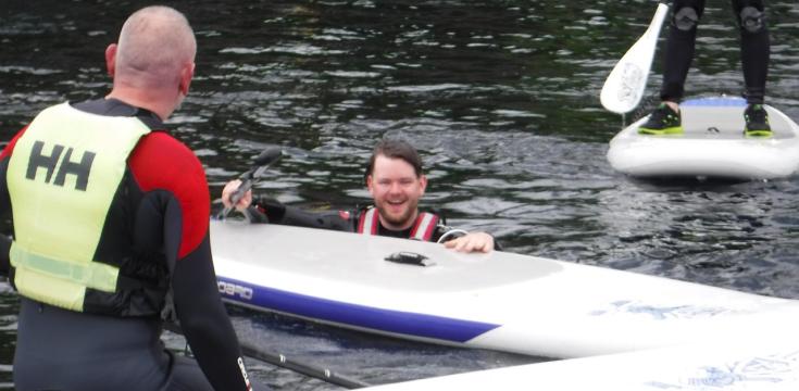 A person trying to get back on to a stand up paddle board