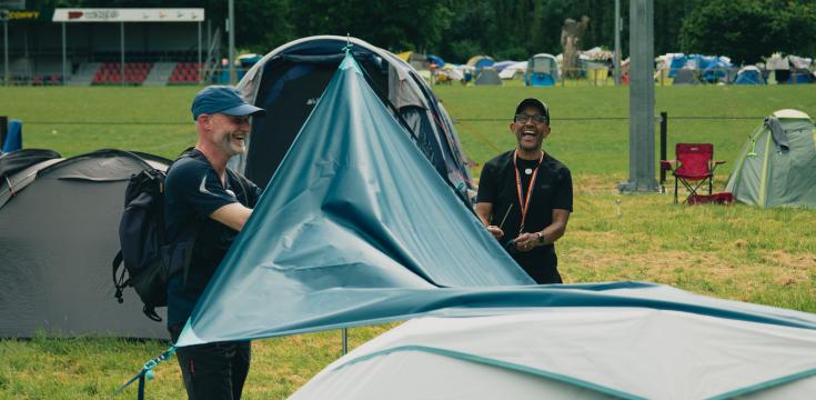 Two men putting up a tent awning
