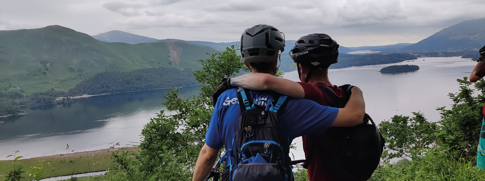 Couple of bikers arm in arm looking over lake